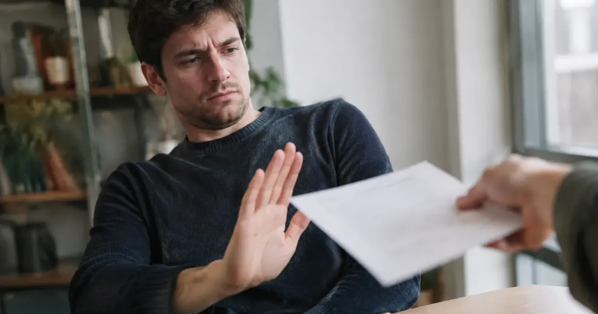 Homme repoussant un contrat de la main