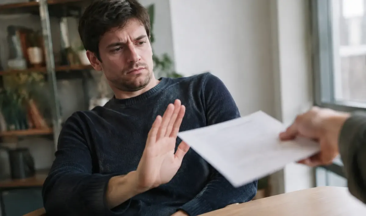 Homme repoussant un contrat de la main